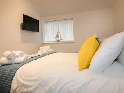 a bedroom with a large bed with a sailboat in the window at Fishermans Loft in Mevagissey