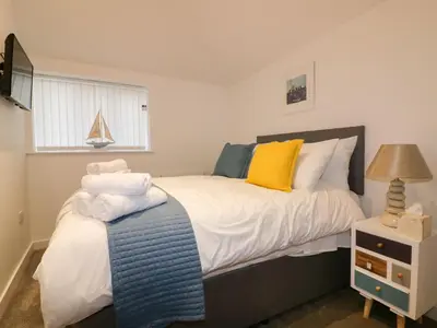 a bedroom with a bed with yellow and blue pillows at Fishermans Loft in Mevagissey