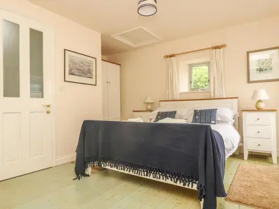 a bedroom with a bed with a black blanket on it at Oreo's Cottage in St. Agnes
