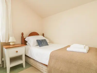 a bedroom with two beds and a table with a lamp at Oreo's Cottage in St. Agnes