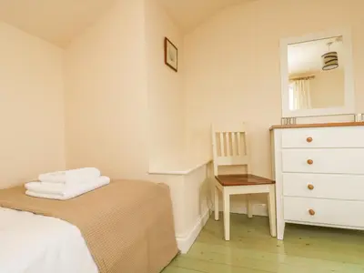a bedroom with a bed and a dresser and a mirror at Oreo's Cottage in St. Agnes