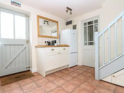 a kitchen with white cabinets and a door at Oreo's Cottage in St. Agnes