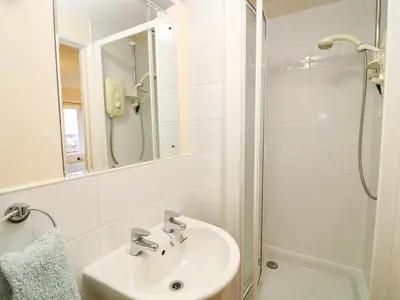 a white bathroom with a sink and a shower at Oreo's Cottage in St. Agnes