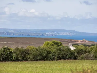 a house in a field with a view of the water at Oreo's Cottage in St. Agnes