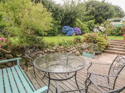 a patio with a table and chairs and flowers at Phenests in Falmouth