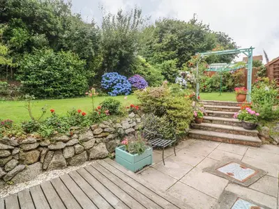 a garden with flowers and a stone wall at Phenests in Falmouth