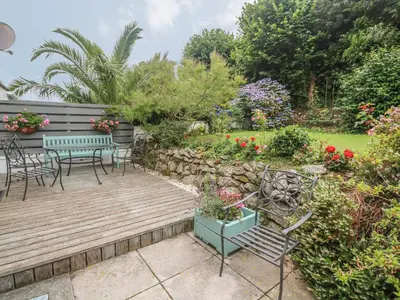 a garden with a wooden deck and chairs and flowers at Phenests in Falmouth