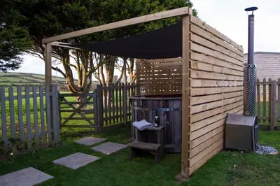 a wooden pergola with a grill in a yard at Wheal Frances-Beautifully Fitted Bungalow Helston Cornwall in Helston