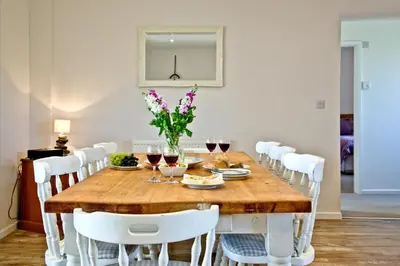 a dining room table with white chairs and wine glasses at Wheal Frances-Beautifully Fitted Bungalow Helston Cornwall in Helston
