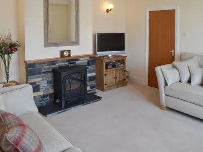 a living room with a fireplace and a television at Littlewood in Saint Columb Major