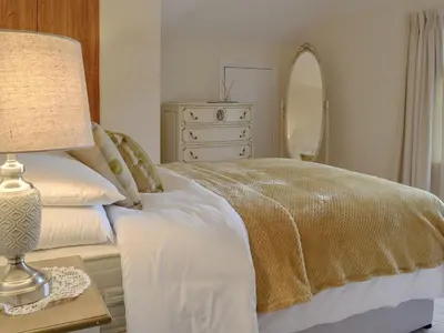 a bedroom with a bed with a lamp and a dresser at Littlewood in Saint Columb Major