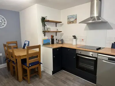 a kitchen with black cabinets and a table and a stove at Corner Cottage Mevagissey in Mevagissey