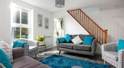 a living room with a couch and two chairs at Corner Cottage Mevagissey in Mevagissey