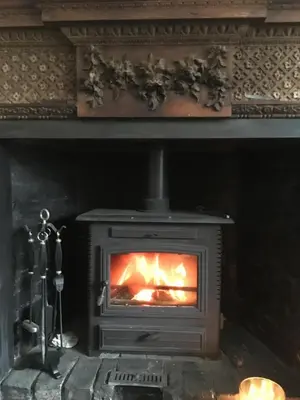 a wood stove with a fire in a fireplace at Park Farmhouse Bed and Breakfast in Washaway