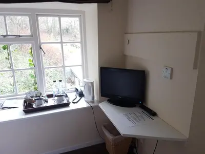a computer on a desk with a laptop and a window at The Mill House in Tintagel