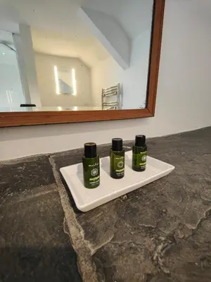 three green bottles on a white tray in front of a mirror at The Mill House in Tintagel