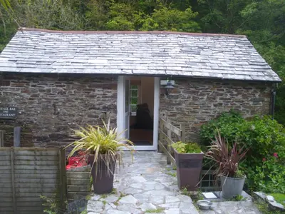 a small stone cottage with potted plants in front of it at The Mill House in Tintagel