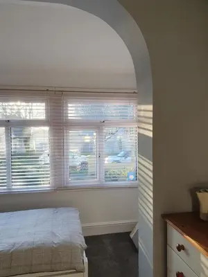 a bedroom with a bed and two windows with blinds at Chynoweth Lodge in Newquay
