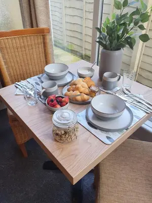 a wooden table with plates and bowls of food on it at Chynoweth Lodge in Newquay