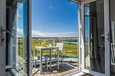 a balcony with a table and chairs and a view of the ocean at Oceanside Lifestyle Hotel in Newquay