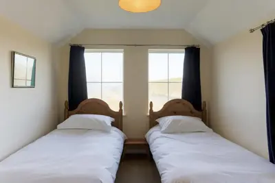 two beds in a room with a window at Chy-an-Lowena in Crantock