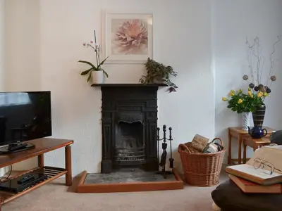 a living room with a fireplace and a tv at Bridgend Cottage in Lostwithiel