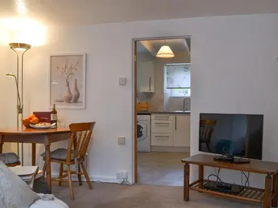a living room with a dining room table and a television at Bridgend Cottage in Lostwithiel