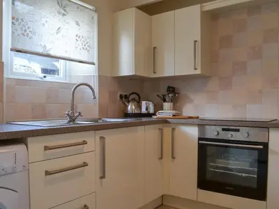 a kitchen with white cabinets and a sink at Bridgend Cottage in Lostwithiel