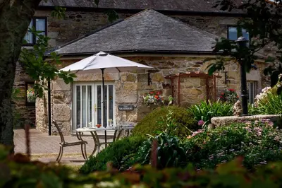a table with an umbrella in front of a house at The Roundhouse in Redruth