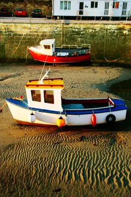 two boats sitting on the sand on the beach at The Roundhouse in Redruth