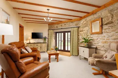 a living room with leather furniture and a stone wall at The Roundhouse in Redruth