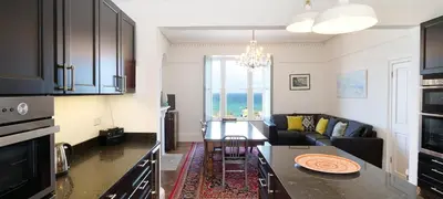a kitchen and living room with a couch and a table at Waves End, St Ives, Hot tub and Parking in St Ives