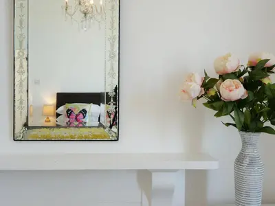 a vase of flowers on a table with a mirror at Waves End, St Ives, Hot tub and Parking in St Ives