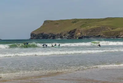 a group of people playing in the waves in the ocean at 12 Westward Flats in Polzeath