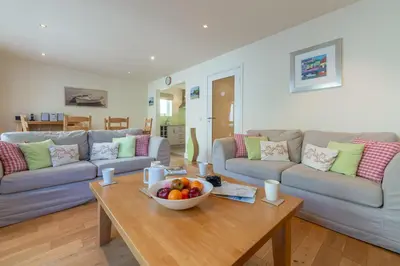 a living room with couches and a bowl of fruit on a table at 4 Pentire Rocks in Polzeath