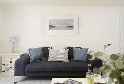 a living room with a gray couch with pillows at Curlew's Cwtch in Wadebridge