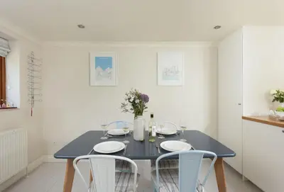 a dining room with a blue table and two white chairs at Curlew's Cwtch in Wadebridge