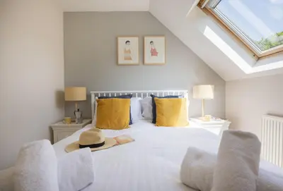a bedroom with a white bed with a hat on it at Curlew's Cwtch in Wadebridge