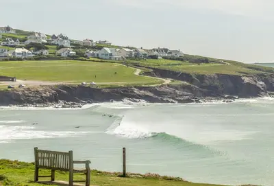 a bench sitting on a hill overlooking the ocean at Curlew's Cwtch in Wadebridge