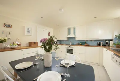 a kitchen with a black table and white cabinets at Curlew's Cwtch in Wadebridge