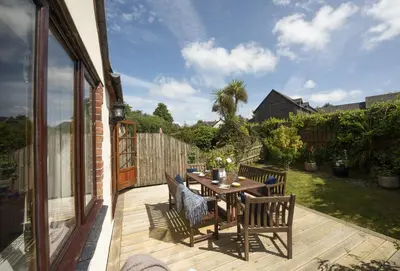 a patio with a table and chairs on a deck at Keepers Cottage in Wadebridge