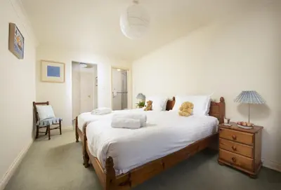 a bedroom with a large bed with two teddy bears on it at Keepers Cottage in Wadebridge