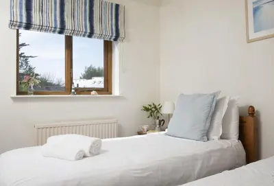 a bedroom with two beds and a window at Keepers Cottage in Wadebridge