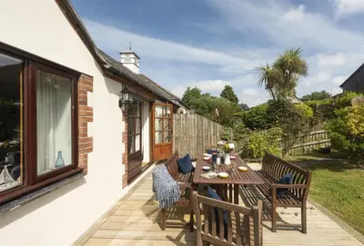 a wooden table and chairs on a patio at Keepers Cottage in Wadebridge