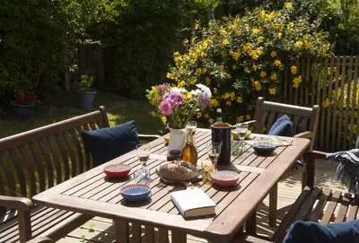 a wooden table with wine glasses and flowers on it at Keepers Cottage in Wadebridge