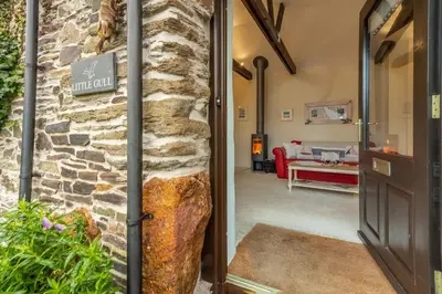 a door leading into a living room with a stone wall at Little Gull in Polzeath