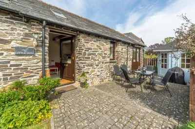 a stone cottage with a table and chairs outside at Little Gull in Polzeath