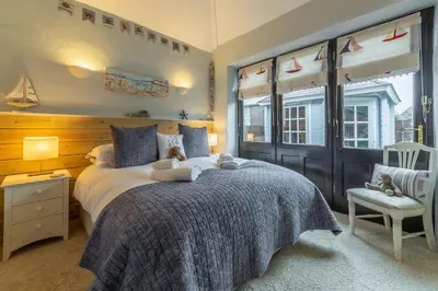 a bedroom with a large bed and a chair at Little Gull in Polzeath