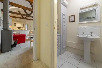 a bathroom with a sink and a living room at Little Gull in Polzeath
