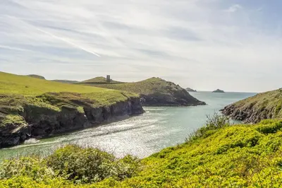 a view of the ocean with a lighthouse on a hill at No2 The Fish Cellars in Port Isaac